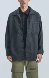 Chaqueta gris de paño con cuello clásico, cierre frontal con botones, bolsillos laterales y corte recto.