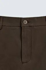 Pantalón chino color beige, de corte recto y tiro medio. Confeccionado en tejido de algodón con elasticidad, con bolsillos laterales y traseros de vivo. Cierre frontal con cremallera y botón.