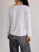 Remera gris de manga larga con cuello redondo y bolsillo en el pecho.