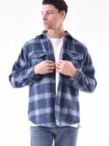 Sobrecamisa negra de corte recto con cuello clásico, cierre frontal con botones a presión, dos bolsillos de parche en el pecho y puños abotonados.