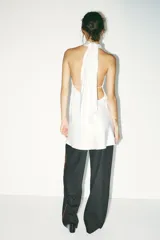 Vestido corto blanco de satén con cuello halter y espalda descubierta.