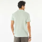 Remera de punto gofrado color celeste con cuello polo y mangas cortas.