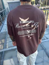 Remera marrón de corte oversize con estampado en la espalda que incluye texto y dibujos de aves.