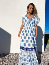 Vestido largo blanco con estampado floral azul, escote en V con bordado y mangas cortas con volados.
