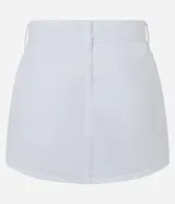 Short pollera corto de jeans blanco con bordados calados (cutout) y bajo festoneado. Presenta trabillas en la cintura y cierre tradicional.