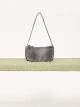 Mini cartera tipo baguette color rosa, realizada en cuero ovino. Tiene acceso mediante un cierre metálico, interior forrado en tejido jacquard con bolsillo y bolsillos frontales con apliques metálicos níquel.