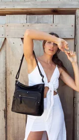 Bandolera negra de símil cuero con dos bolsillos frontales con cierre y detalles de tachas metálicas. Incluye un bolsillo trasero, tres bolsillos internos y correa larga regulable.