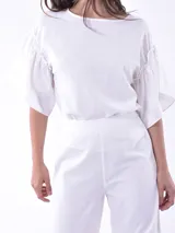 Blusa negra de mangas cortas con volados y escote redondo.