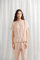 Blusa blanca de lino, corte holgado, con cuello redondo y cierre frontal con botones.