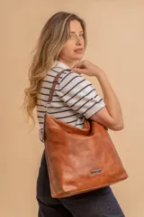 Cartera bandolera color marrón claro, de símil cuero, con dos divisiones internas, asa corta fija y correa larga regulable.