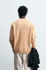 Sweater color arena con textura jaspeada, de corte recto, cuello redondo y mangas largas con terminaciones acanaladas.