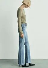 Pantalón de jean celeste de tiro medio, corte acampanado, con cinco bolsillos, cierre de cremallera y botón, trabillas y bajo deshilachado.