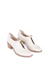 Zapato de cuero texturizado color blanco hueso, con punta cuadrada, detalle de hebilla dorada y taco de madera.