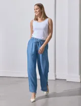 Pantalón celeste de lyocell, corte ancho, con cintura elastizada ajustable con cordón y ruedo desflecado con tajos laterales.