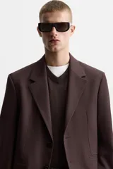 Blazer color borgoña de corte regular, con cuello de solapas de muesca, manga larga con puños abotonados, bolsillos de doble vivo en la cadera, bolsillo interior, abertura en el centro de la espalda y cierre frontal con botonadura.