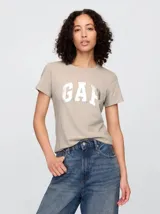 Remera color gris topo con logo GAP plateado en el frente, de corte recto y mangas cortas.