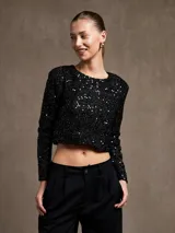 Top corto negro con lentejuelas, de mangas largas y cuello redondo.