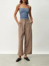 Pantalón de vestir color negro, de corte recto, con bolsillos laterales y traseros. Se ajusta a la cintura con cinturón de cuero marrón.