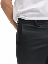 Bermuda de lino color negro, corte recto, con bolsillos laterales y cierre frontal.