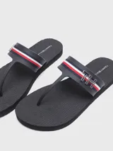 Sandalias de playa color azul marino con tiras de dedo y una banda transversal decorada con las icónicas rayas globales de Tommy Hilfiger y un monograma metálico 'TH'. Cuentan con suela de goma plana y capellada sintética.