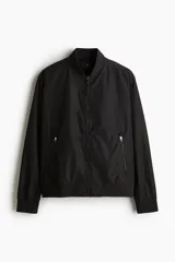 Campera bomber negra liviana con cuello elevado acanalado y cierre delantero. Tiene bolsillos laterales y un bolsillo interior, todos con cierre. Los puños y el bajo son acanalados.