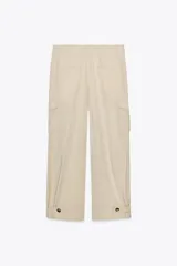 Pantalón color beige de tiro alto con bolsillos delanteros, bolsillos de plastrón con solapa laterales y falsos bolsillos de vivo en la espalda. Bajo acabado con trabilla y botón. Cierre frontal con cremallera y botón.