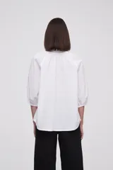 Blusa blanca de algodón con escote en V con lazos, mangas 3/4 abullonadas y corte holgado.