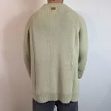 Sweater verde oliva de tejido grueso con cuello alto.