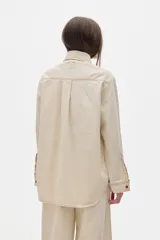 Camisa de jean color crudo, corte oversized, con botones rojos y pespuntes a contratono.