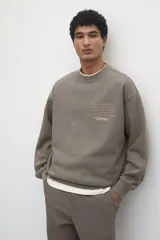 Buzo de algodón pesado color marrón con efecto lavado e interior cepillado suave. Modelo con diseño estampado, cuello redondo y hombros caídos. Remate acanalado en cuello, puños y bajo. Corte holgado.