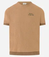 Remera de manga corta color marrón claro, con cuello redondo y ribete en puños y ruedo. Presenta un bordado con la frase "Savane tropicale" en el pecho.