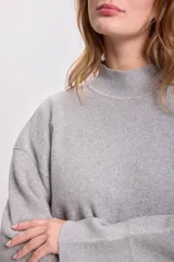 Sweater de punto color gris claro, de cuello alto y corte holgado.