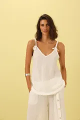 Musculosa blanca de lino con breteles trenzados y detalle de flecos en el escote.