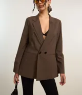 Blazer marrón de poliéster y viscosa, de corte amplio y estructura de sastrería, con solapas en el cuello, doble abotonadura, bolsillos falsos y pinzas.