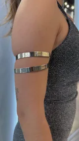 Brazalete plateado de metal con diseño de doble aro para el brazo.