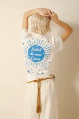 Remera blanca de algodón con estampado en la espalda de un sol azul con la frase "Soleil de mon Coeur".