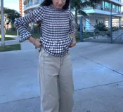 Blusa de manga larga con cuello alto y fruncido en el torso y puños. Estampado a cuadros vichy en tonos marrón y blanco.