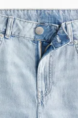 Jean de cinco bolsillos en denim rígido color azul claro, con pierna ancha y corte holgado de muslo a bajo. Cintura clásica con cierre y botón.