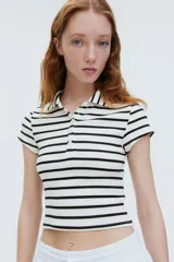 Remera polo de manga corta con cuello clásico y tapeta de botones. Diseño a rayas horizontales en blanco y negro, de corte entallado y tejido acanalado.