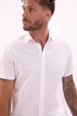 Camisa blanca de manga corta con cuello clásico y cierre frontal con botones.