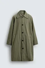 Trench color verde oliva de tejido técnico, corte relaxed fit, cuello solapa, manga larga, bolsillos laterales y abertura en la espalda.