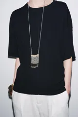 Remera blanca de punto liso, corte amplio, cuello redondo y manga corta.