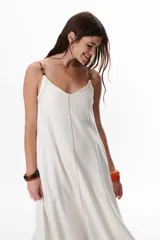 Vestido largo color crudo con breteles finos y costuras a la vista en color azul.