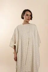 Ruana marrón con diseño a cuadros blancos, terminación envivada y flecos cortos.