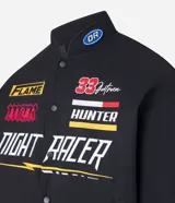 Campera negra con cuello alto, cierre de botones y estampado estilo racing con logos y textos en amarillo, rojo y blanco. Tiene bolsillos laterales y mangas largas con detalles estampados. Marca Blue Steel.