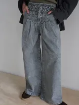 Pantalón vaquero de corte ancho, color crudo, con cintura alta y detalle de costuras cruzadas en la parte superior.