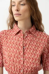 Maxi vestido rojo con estampado de rombos, corte camisero, cuello clásico, mangas cortas abullonadas con puños elásticos, cintura elastizada y falda larga escalonada.