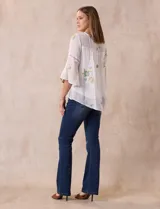 Blusa blanca de gasa con bordados florales, corte holgado, mangas 3/4 acampanadas con detalle de puntilla y forro interno.