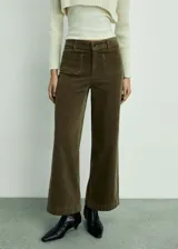 Pantalón de pana color marrón, de corte culotte y tiro alto, con cierre de cremallera y botón, trabillas, dos bolsillos de parche delanteros y dos bolsillos de parche traseros.