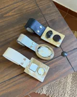 Cinto de ecocuero con hebilla redonda de alpaca y nácar.